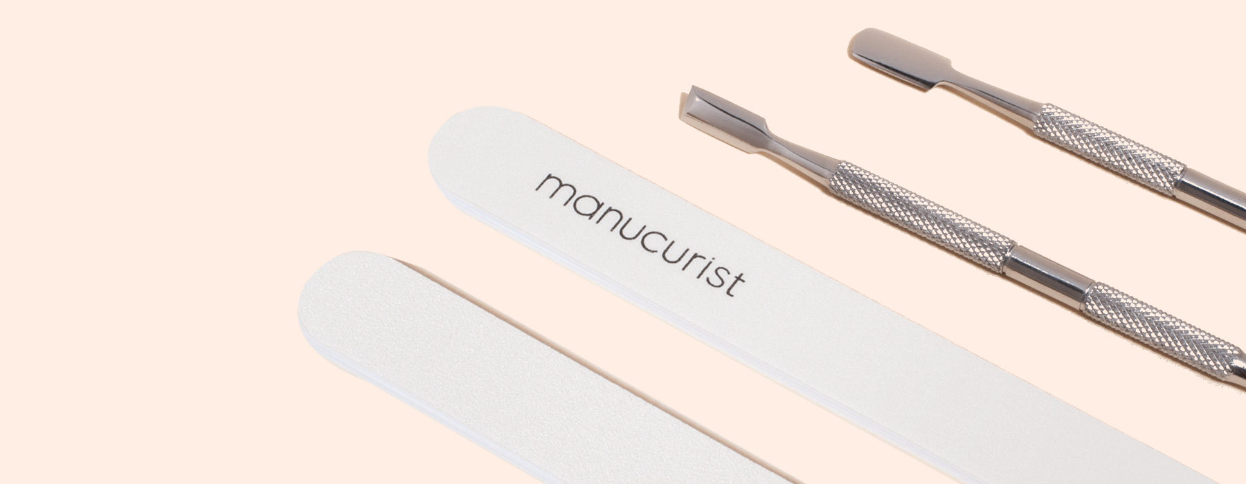 A manicure set with two metal cuticle pushers, two white nail files labeled manucurist, and a blue oval tool marked M7XQ on a light beige background.