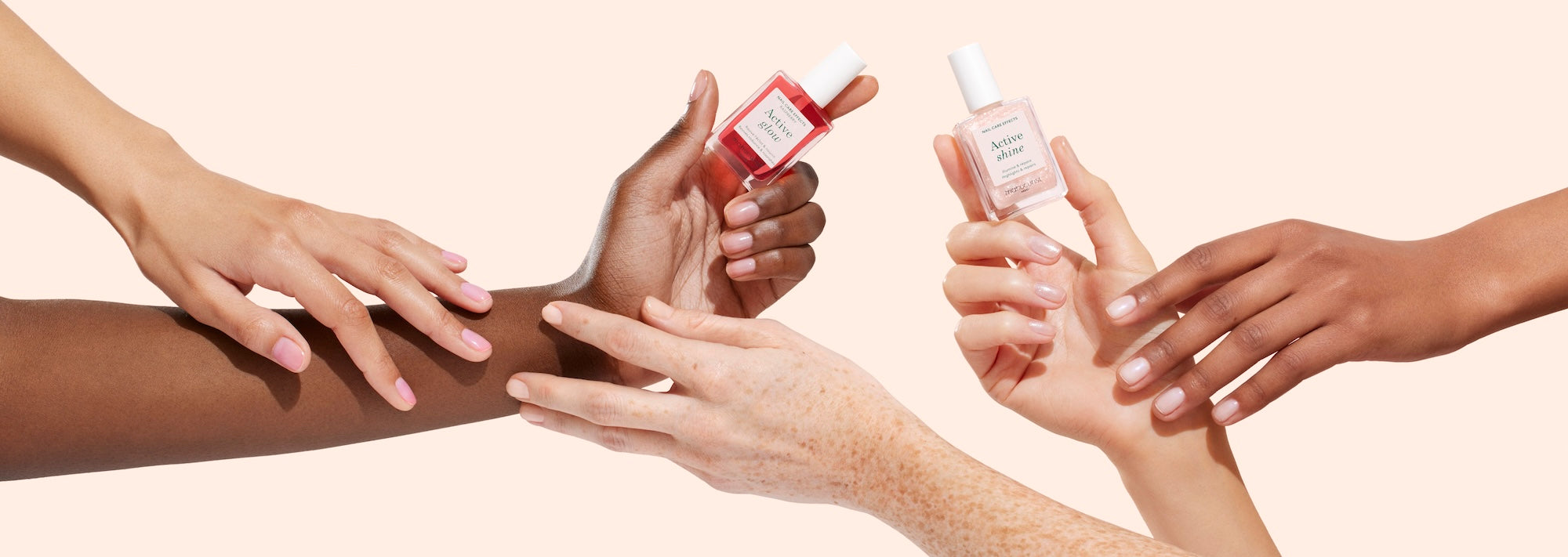 Three pairs of hands in varying skin tones reaching toward each other, each holding a bottle of nail polish in pink and red shades against a light beige background.