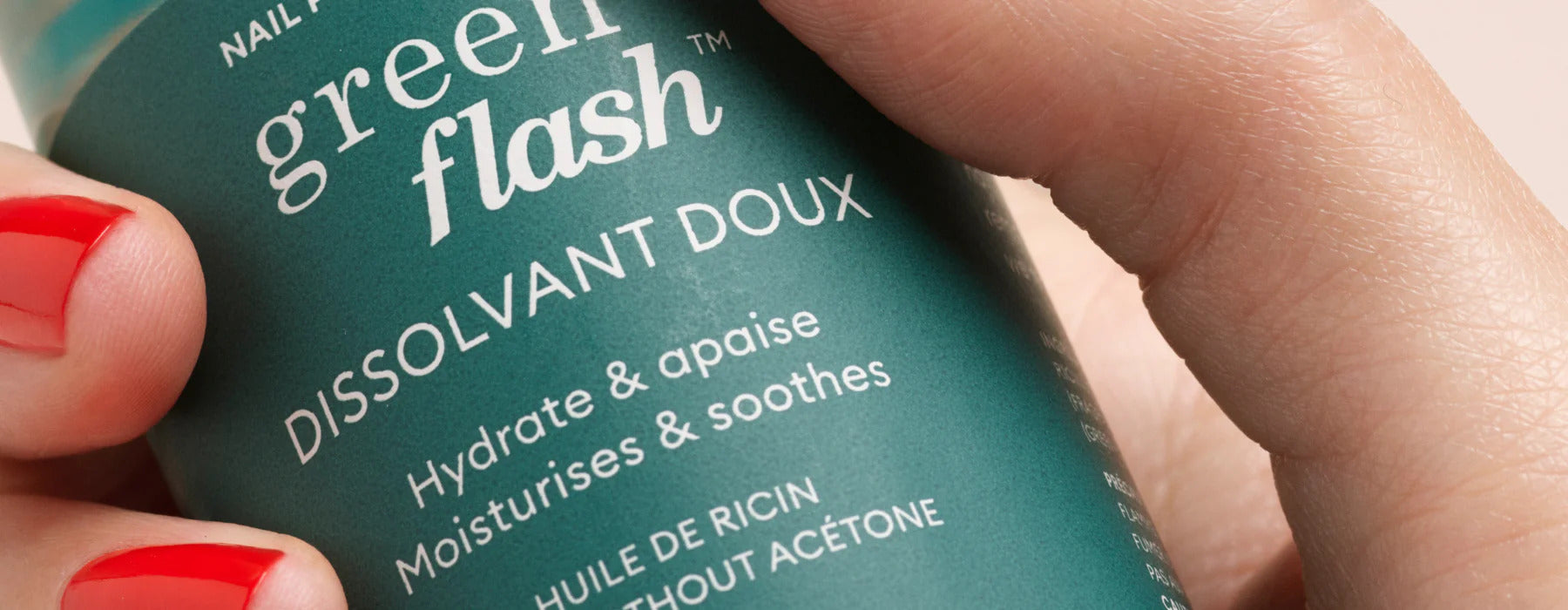 A hand with red nail polish holds a green bottle labeled green flash DISSOLVANT DOUX Hydrate & apaise Moisturises & soothes in white text.