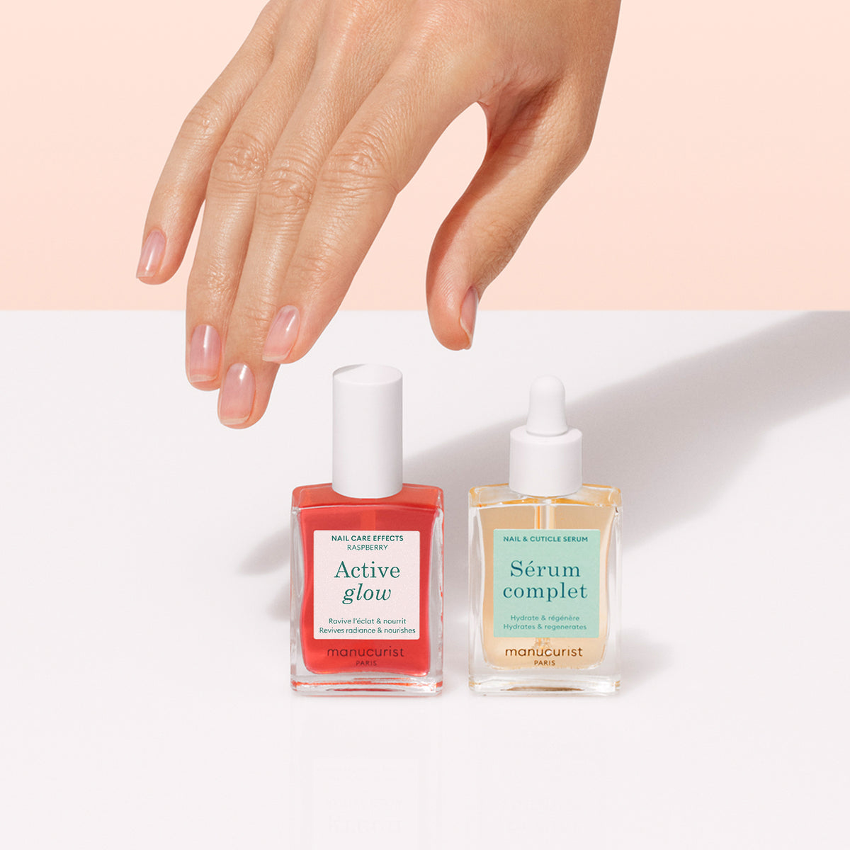A hand hovers above two square glass bottles from Manucurist&