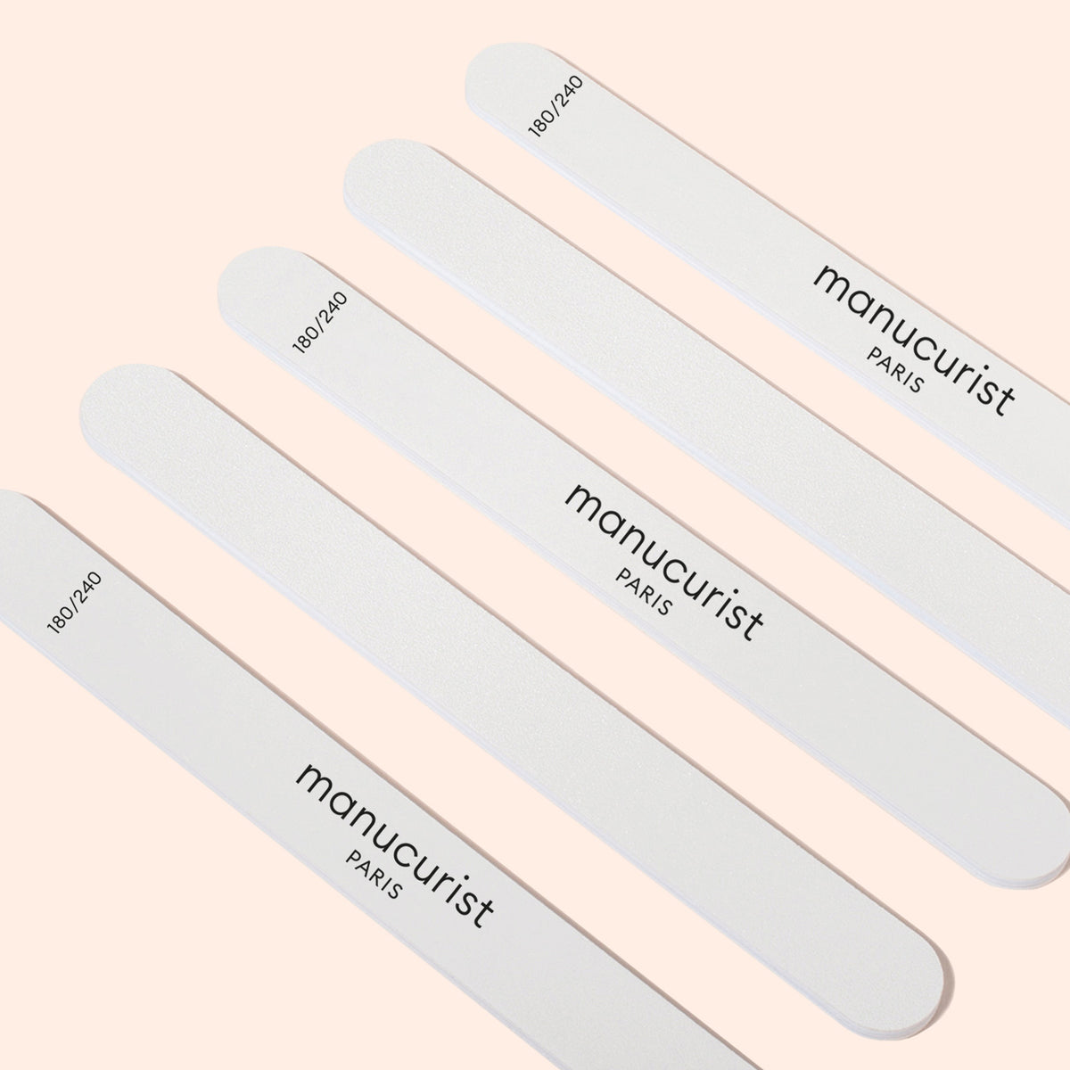 Five Manucurist 180/240 emery boards for fragile nails (pack of 5) are displayed diagonally on a light beige background—ideal for shaping sensitive or brittle nails.