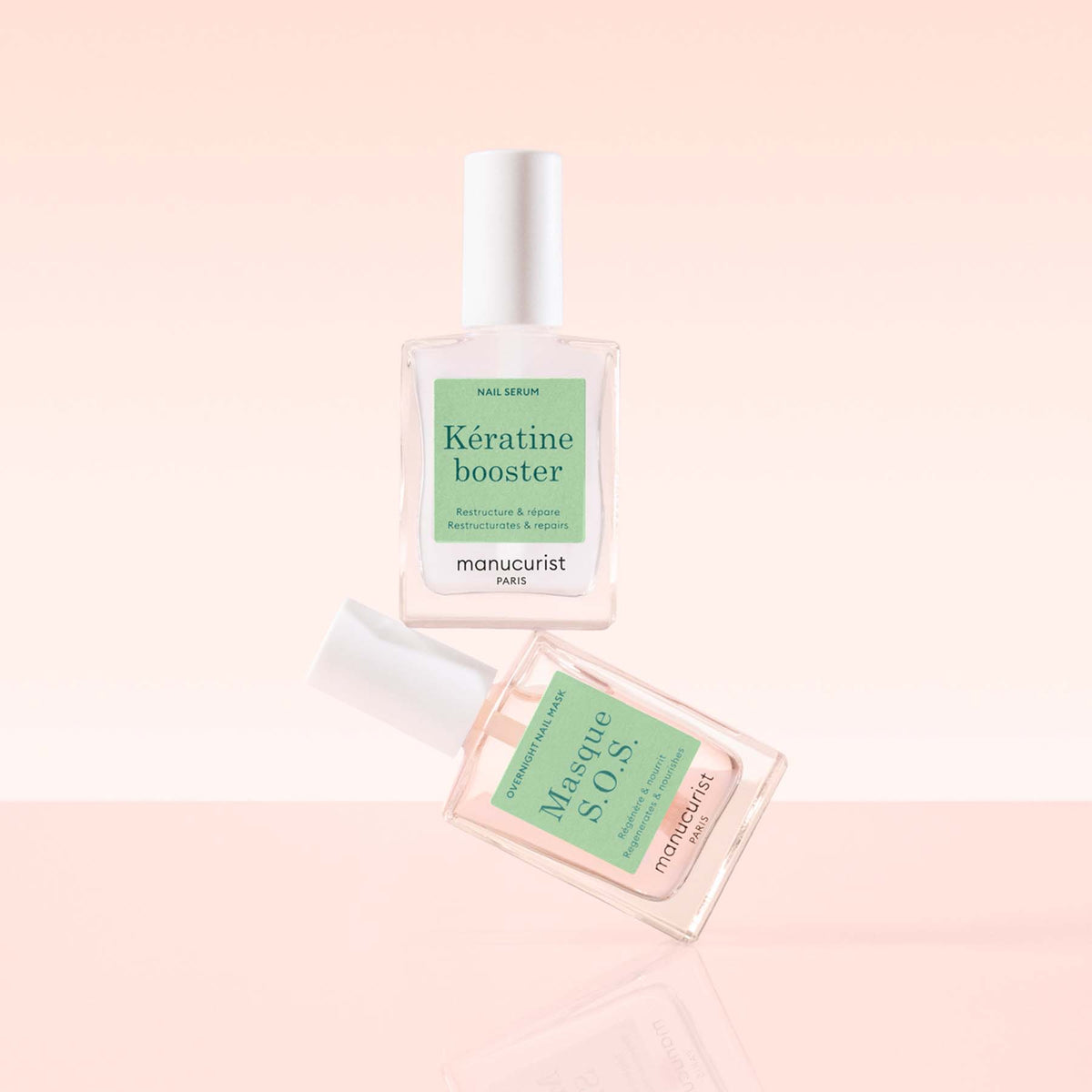 Two clear Manucurist Day Night Duo nail care bottles with white caps float against a soft pink gradient background. One is for keratin boosting and the other is a nourishing nail mask.