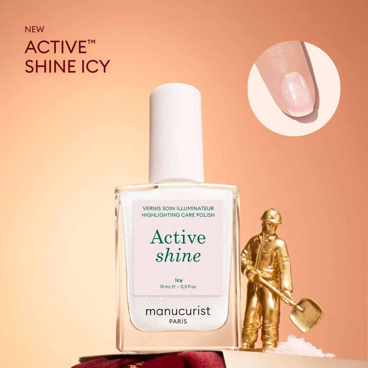 A bottle from the Manucurist Advent Calendar Time to Shine! collection rests on a snowy surface beside a gold figurine holding a shovel, capturing festive nail care excitement. An inset close-up displays the iridescent polish on a fingernail against a pink backdrop—making it an ideal treat for any Advent Calendar surprise.