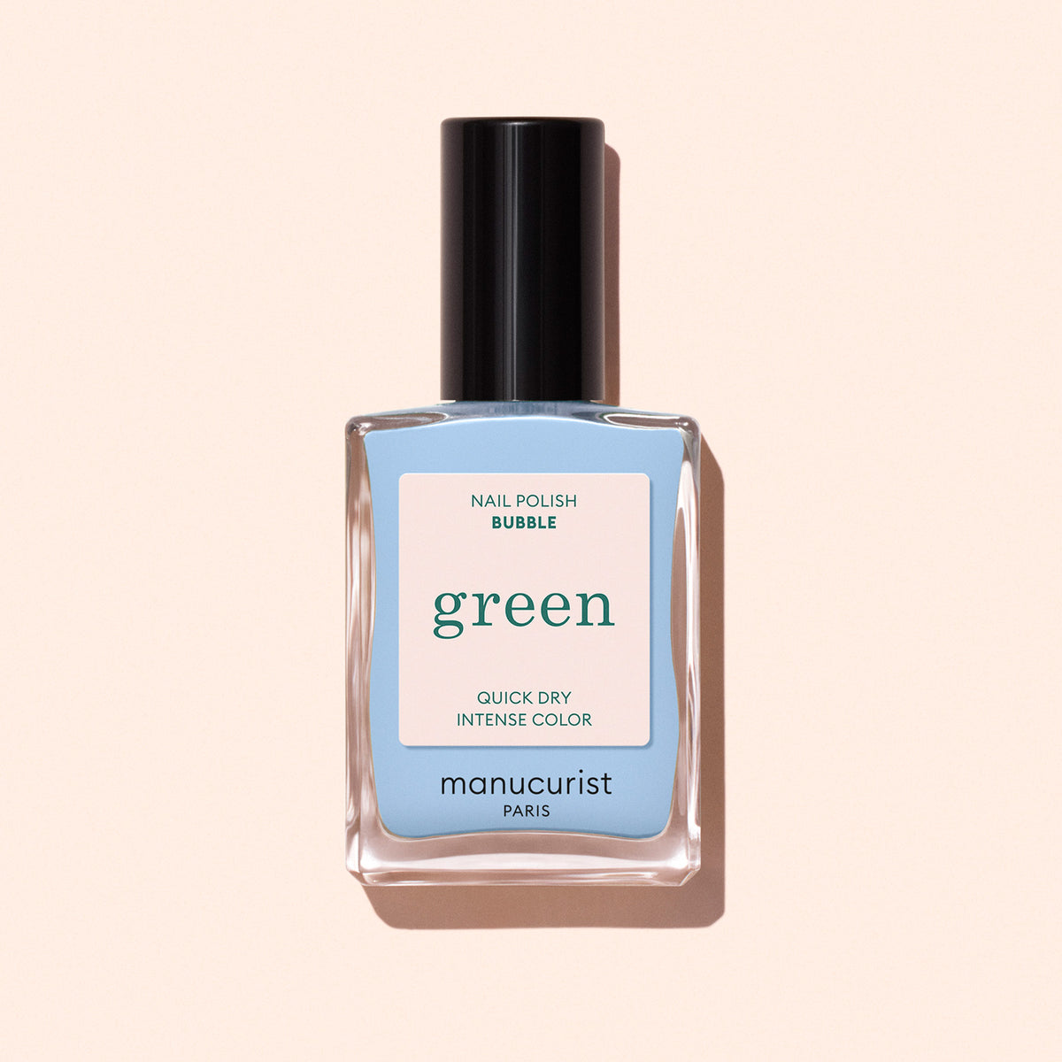 A bottle of Manucurist Bubble nail polish, featuring a pastel blue shade with grey undertones, black cap, and clear glass bottle, displayed against a light beige background.