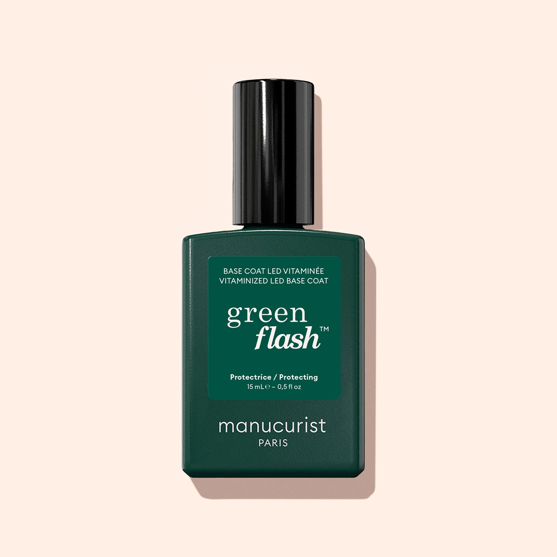 A green bottle of Manucurist Vitaminised Base Coat Green Flash™ with a black cap is shown against a light beige background.