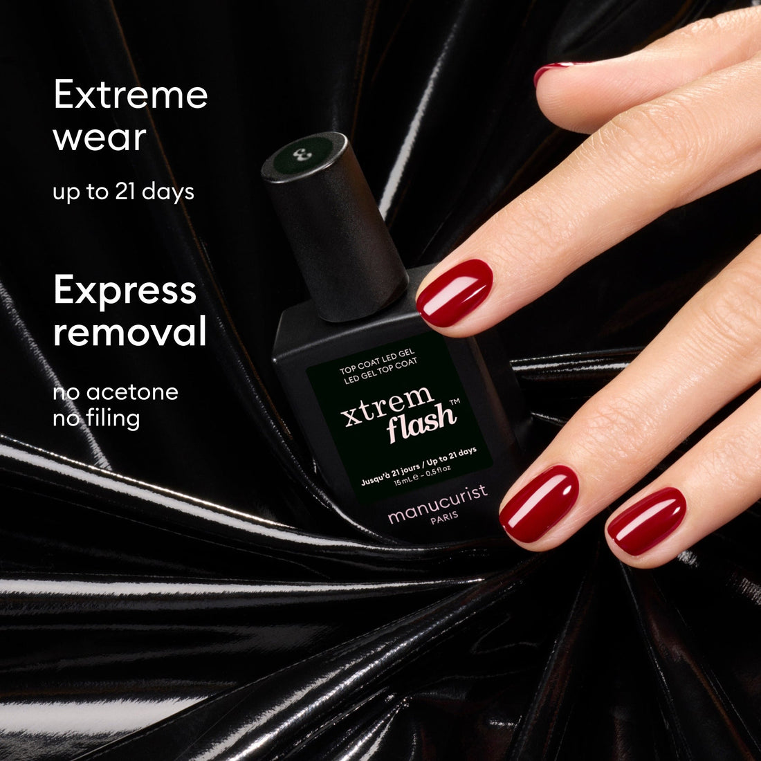 A hand with glossy red nails holds a black bottle of Manucurist Xtrem Flash™ Gel Top Coat against a shiny black background. Text: Up to 21 days of extreme wear. Quick removal—no acetone, no filing needed.