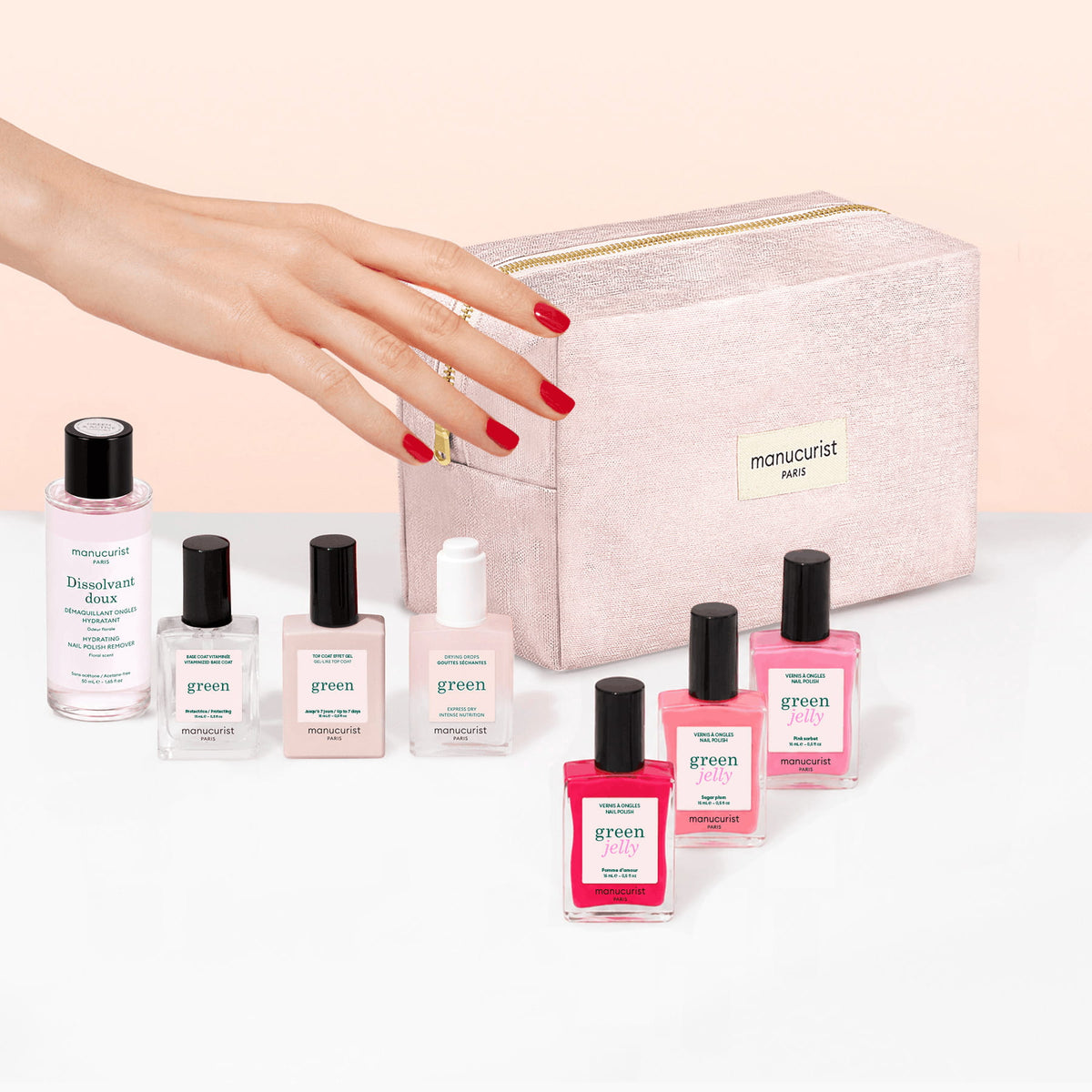A hand with red nails reaches toward the Manucurist Starter Kit - Jelly Nail Polish, featuring gel-effect polish bottles and a remover, all arranged beside an organic cotton pouch labeled manucurist PARIS on a white surface.