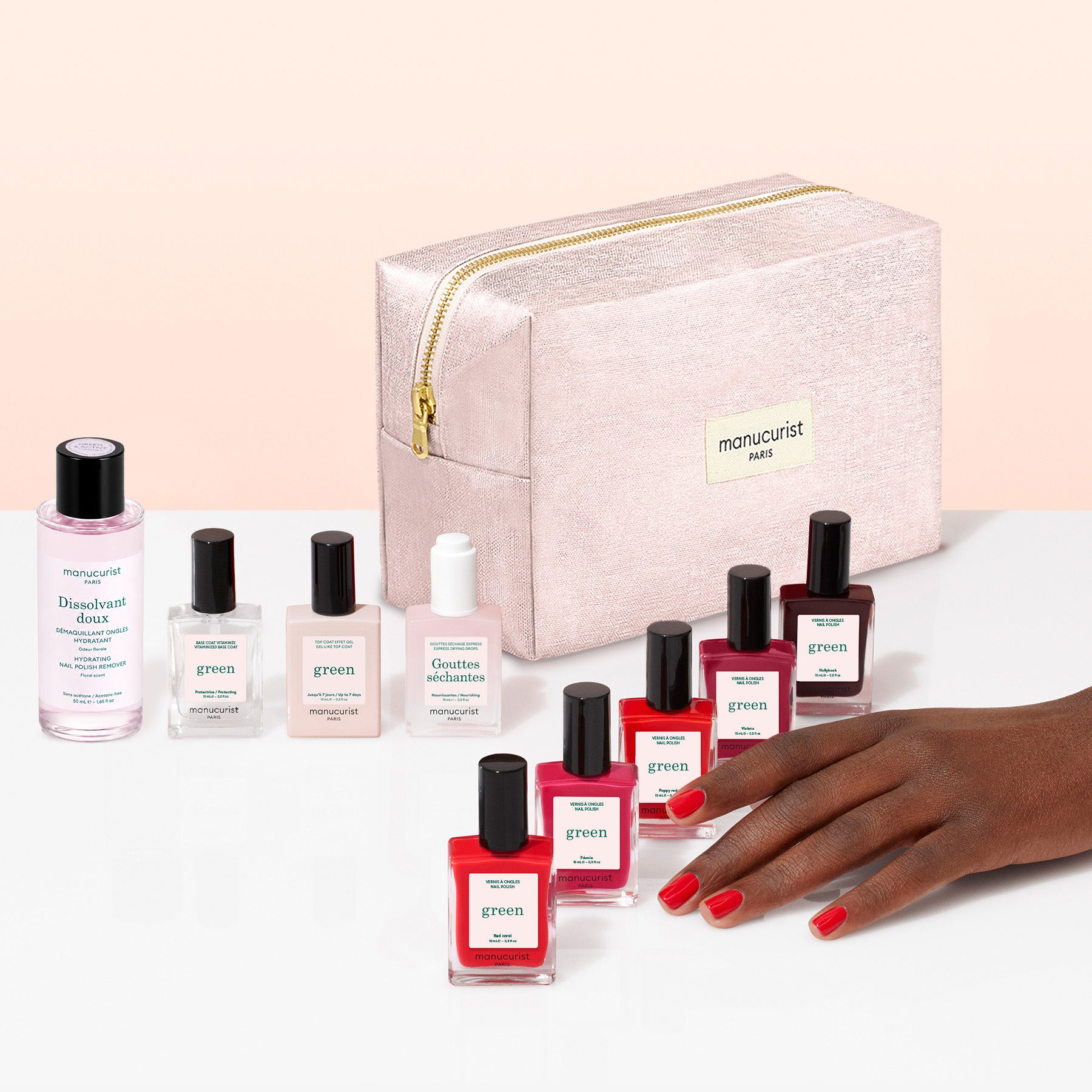 A hand with red nail polish is shown near manicure products, including Manucurist gel-effect nail polishes in various shades, bottles of nail care solutions, and a pink zippered bag labeled Manucurist. The Manucurist Super Starter Kit provides everything you need for flawless nails, all neatly organized in an organic cotton pouch.