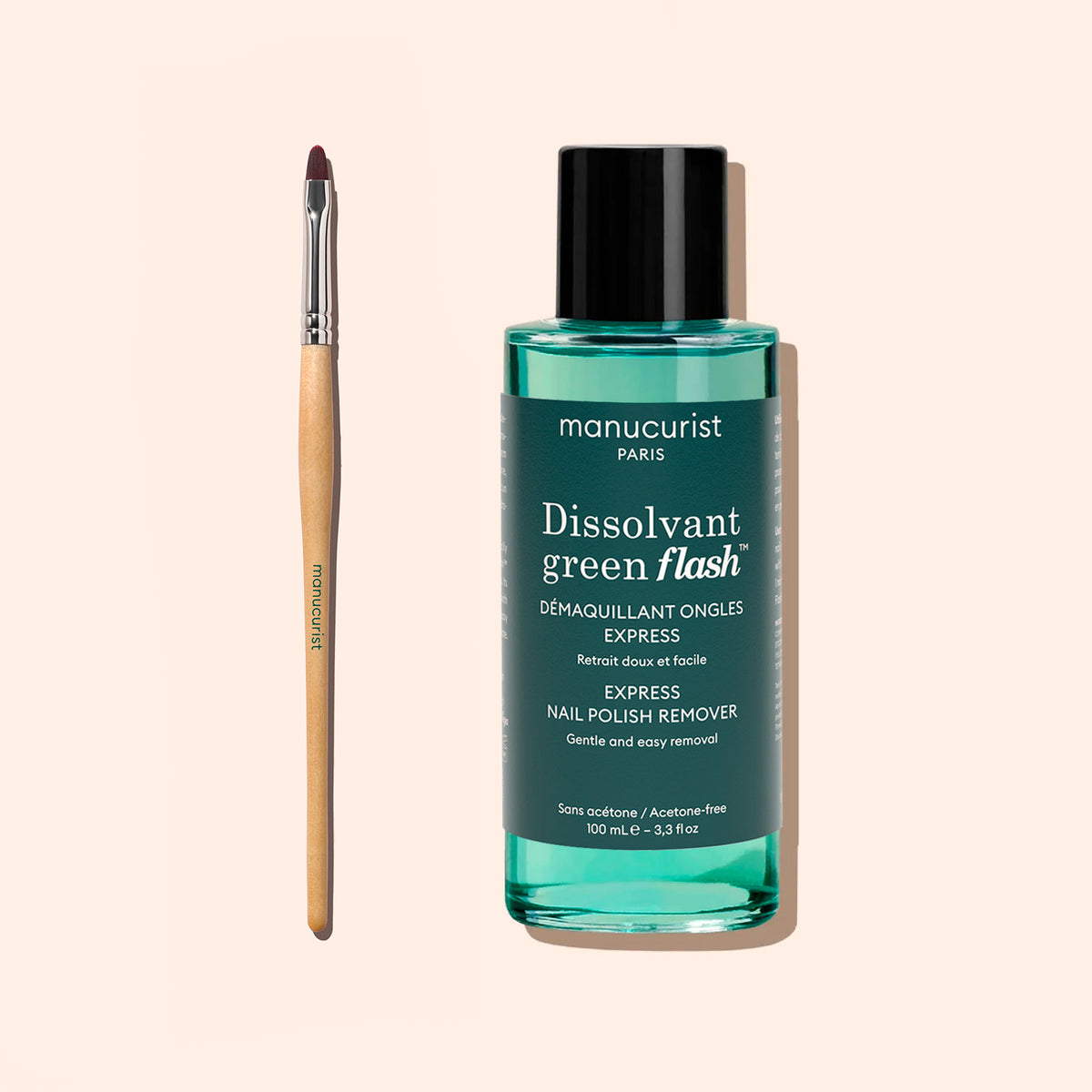 A bottle of Manucurist Green Flash nail polish remover is positioned upright beside the Manucurist Flat Brush, which features a wooden handle and is ideal for precise manicure or cuticle care, with both products displayed against a light beige background.