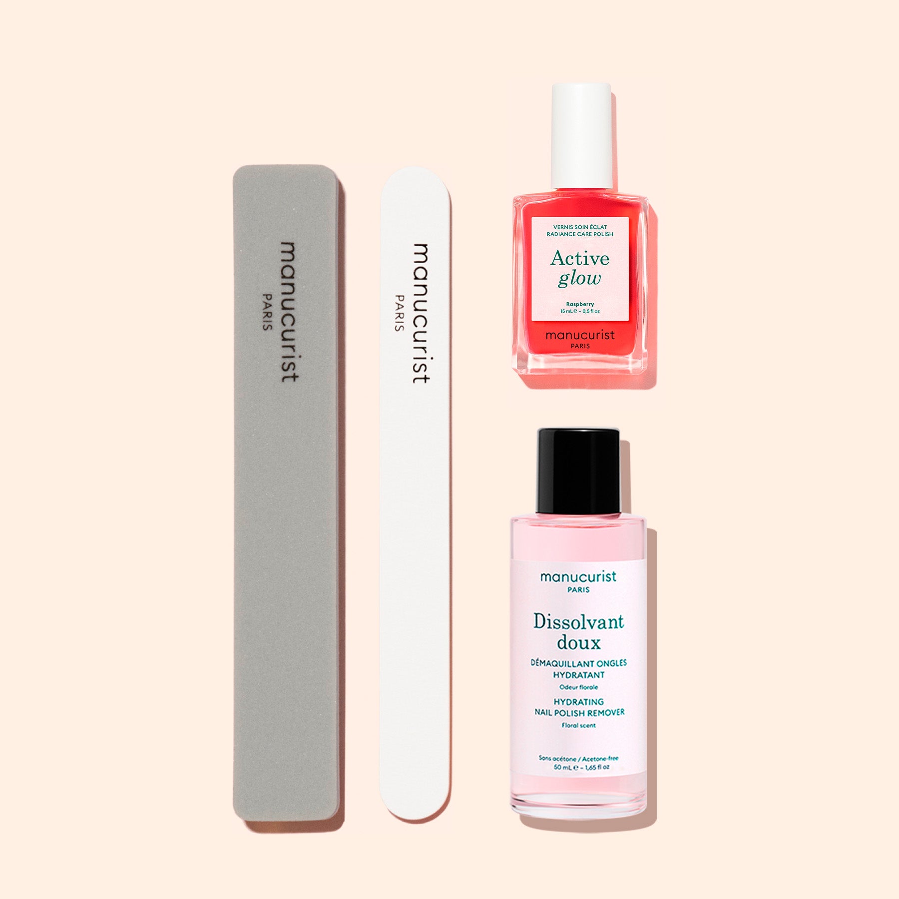 Two nail files and two bottles—one pink and one coral—from the Manucurist Active™ Discovery Kit are arranged neatly on a beige background, offering the perfect essentials to elevate your nail care routine and hydrate your nails for a polished finish.