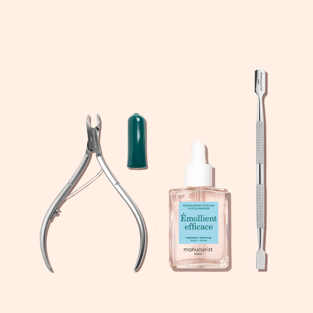 A professional-quality Manucurist Cuticle Nippers, a green cap, a bottle of Émollient efficace cuticle softener, and a double-ended stainless steel cuticle pusher are arranged neatly on a light pink background.
