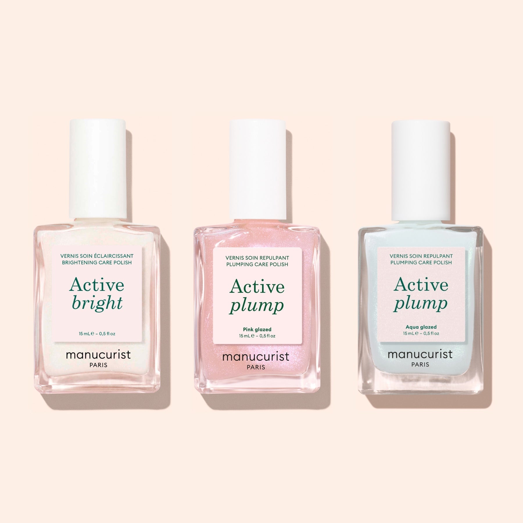 Three square-based nail polish bottles with white caps by Manucurist are shown. Labels read Active Bright (clear), Active Plump (pink), and Active Plump Aqua Glazed (light blue)—volumising care for hydrated nails.
