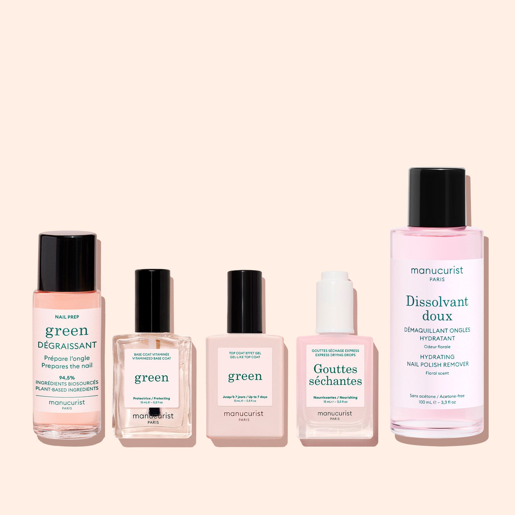 Three Manucurist Green™ products—a base coat, top coat, and nail polish remover—are displayed in glass and plastic bottles against a pale pink background. Labels feature the brand and product names in French and English.