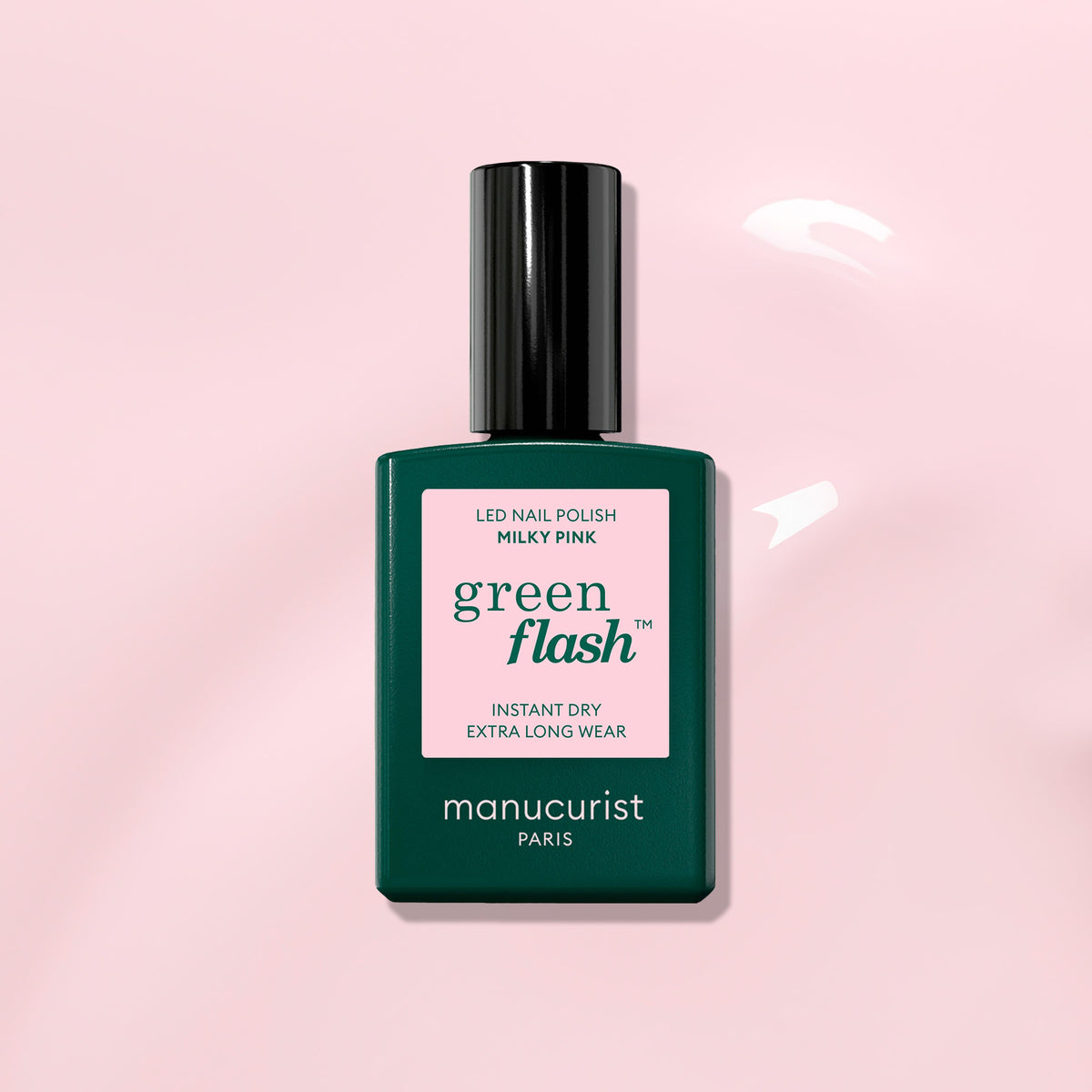 A bottle of Manucurist Milky Pink gel polish with a dark green cap and label sits against a light pink background featuring glossy liquid swirls.