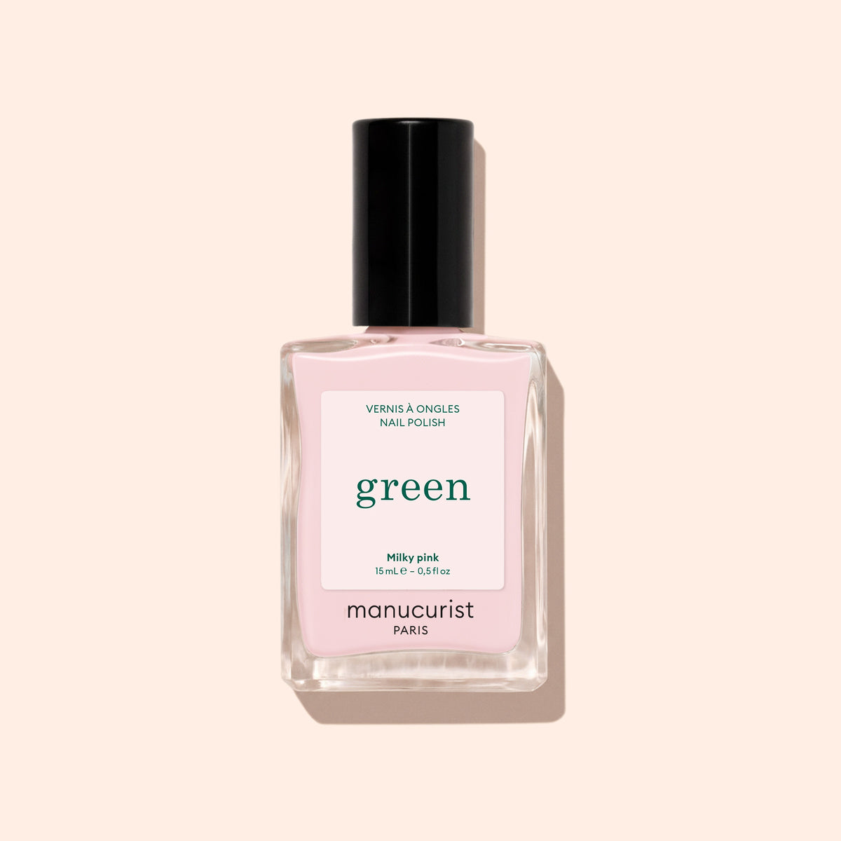 A bottle of Manucurist Milky Pink nail polish with a black cap is displayed on a light beige background.