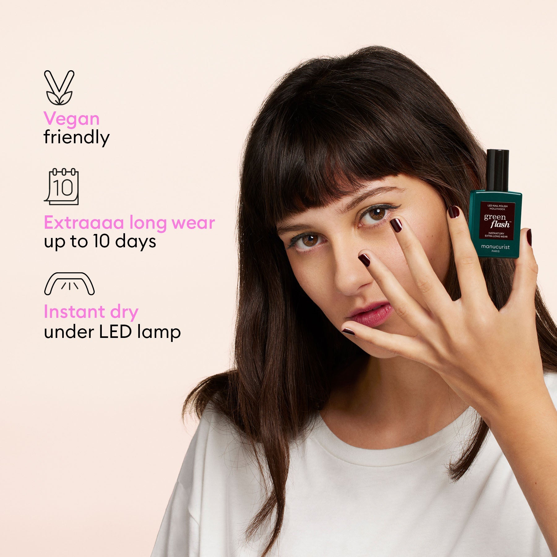 A woman with dark hair displays her black-painted nails while holding the Manucurist Welcome Kit Green Flash™, which is vegan friendly, offers extra long wear up to 10 days, and dries instantly under an LED lamp.