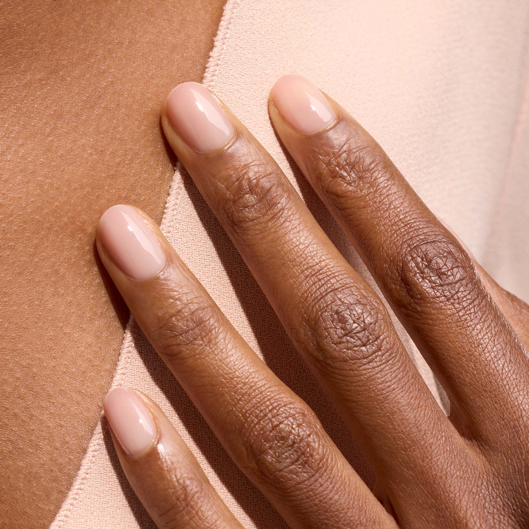 A close-up of a medium brown hand with neatly manicured nails painted in Manucurist-test&