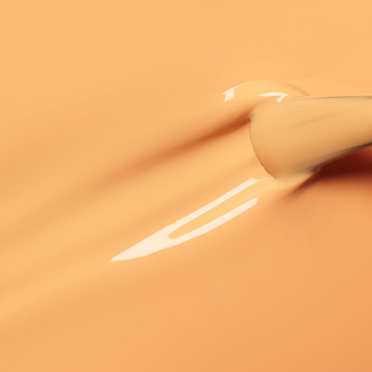 A close-up of a Manucurist Abricot nail polish brush applying smooth, glossy pastel orange polish, leaving an even layer with a shiny finish.