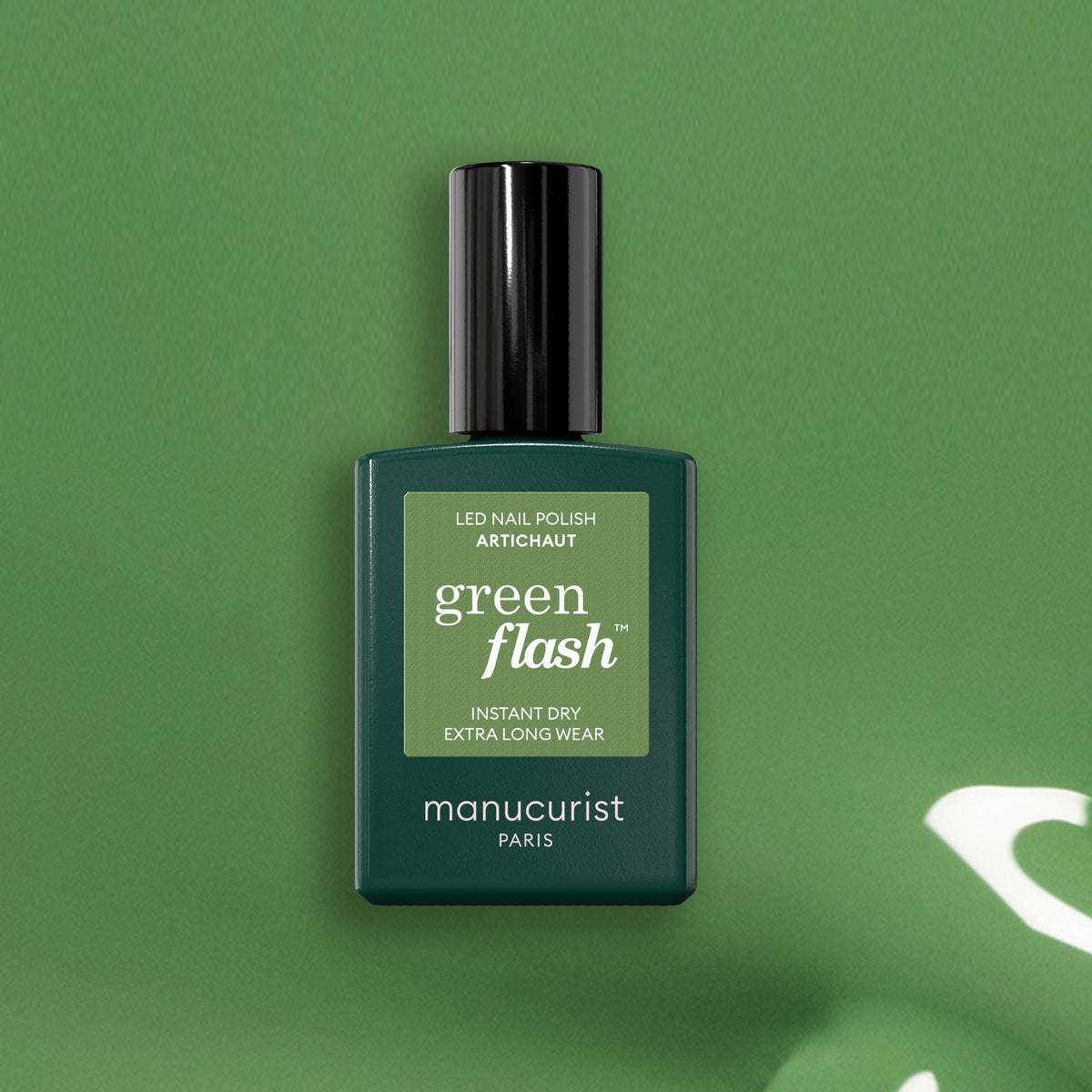 A bottle of Manucurist Artichoke sits upright on a matching green background. The label reads: LED Nail Polish, Instant Dry Extra Long Wear, showcasing a chic, herbal green allure.