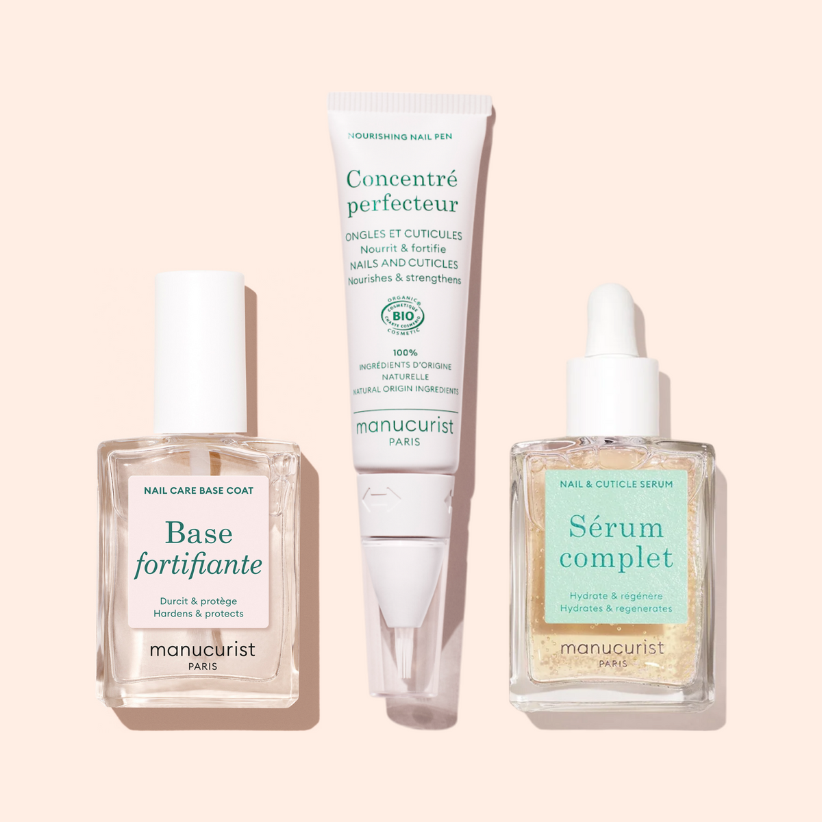 Three Manucurist products on a beige background: Force Nail Hardener, Concentré Perfecteur tube, and Sérum Complet dropper—each an advanced nail treatment to help strengthen nails.