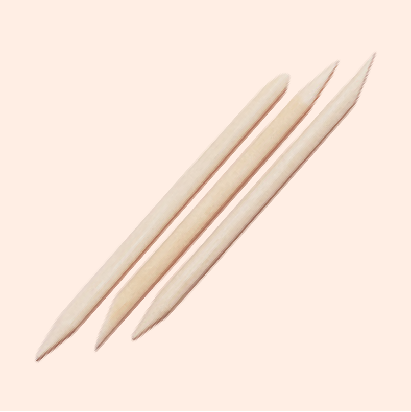 Three Manucurist-test Wood Cuticle Pusher x3, featuring pointed and angled tips, are displayed diagonally on a light beige background.