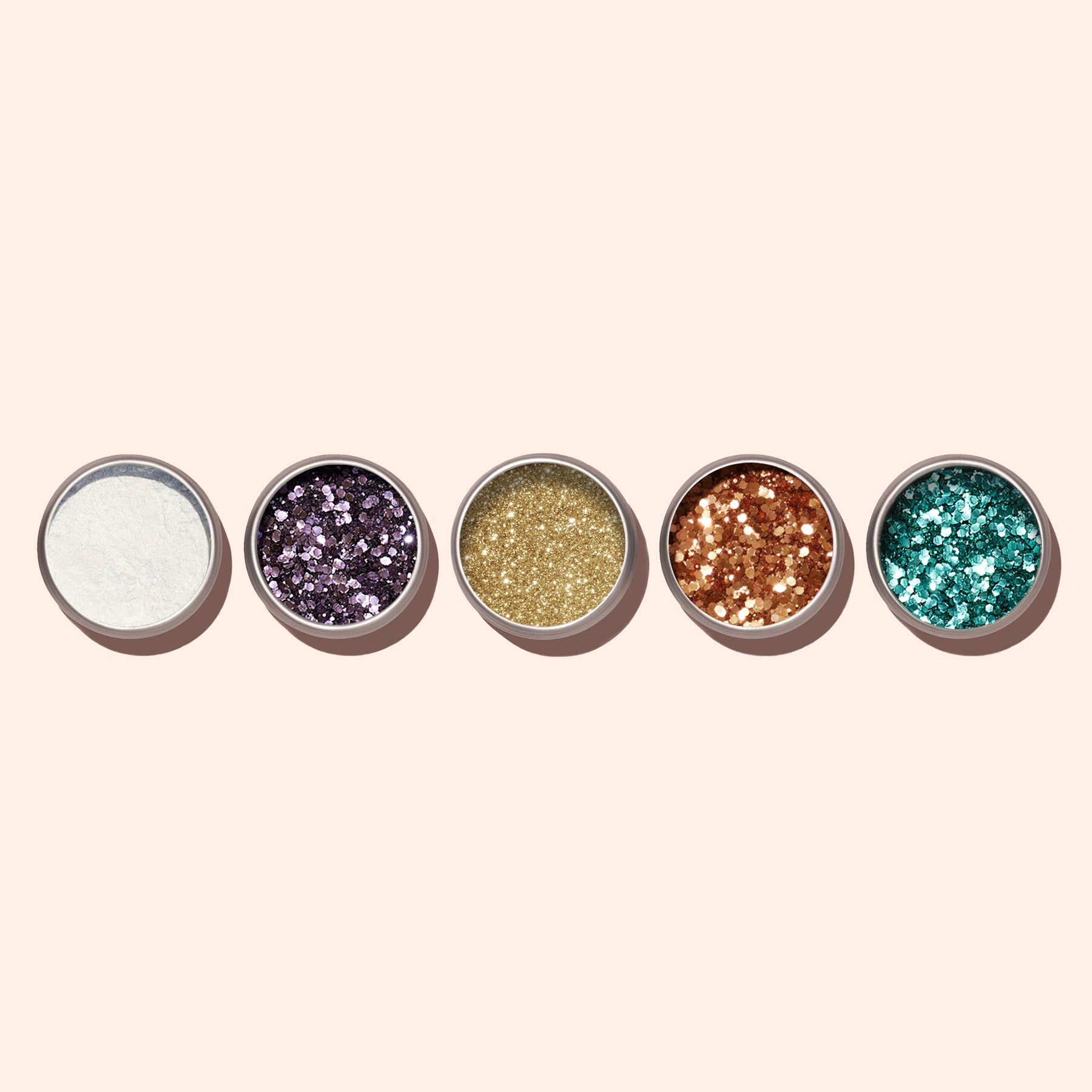 Five small round containers of Manucurist Turquoise biodegradable glitter are arranged in a row on a light beige background, showcasing different sparkling colors and textures—ideal for enhancing your nail art.