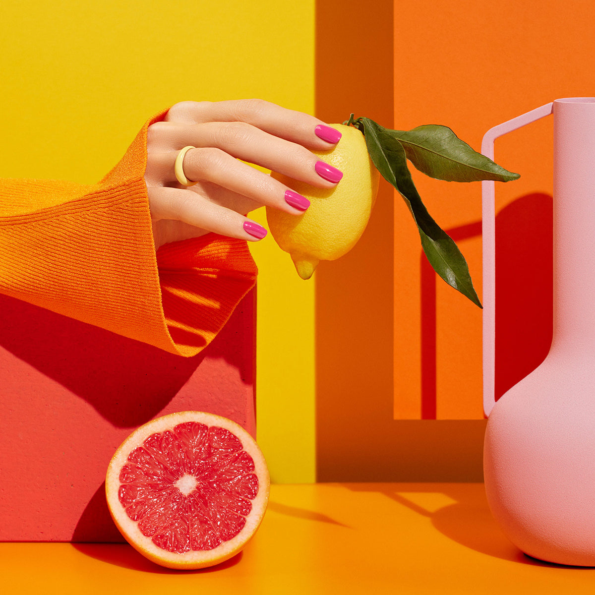 A hand with vibrant summer nail art from Manucurist’s Smile! collection holds a lemon.