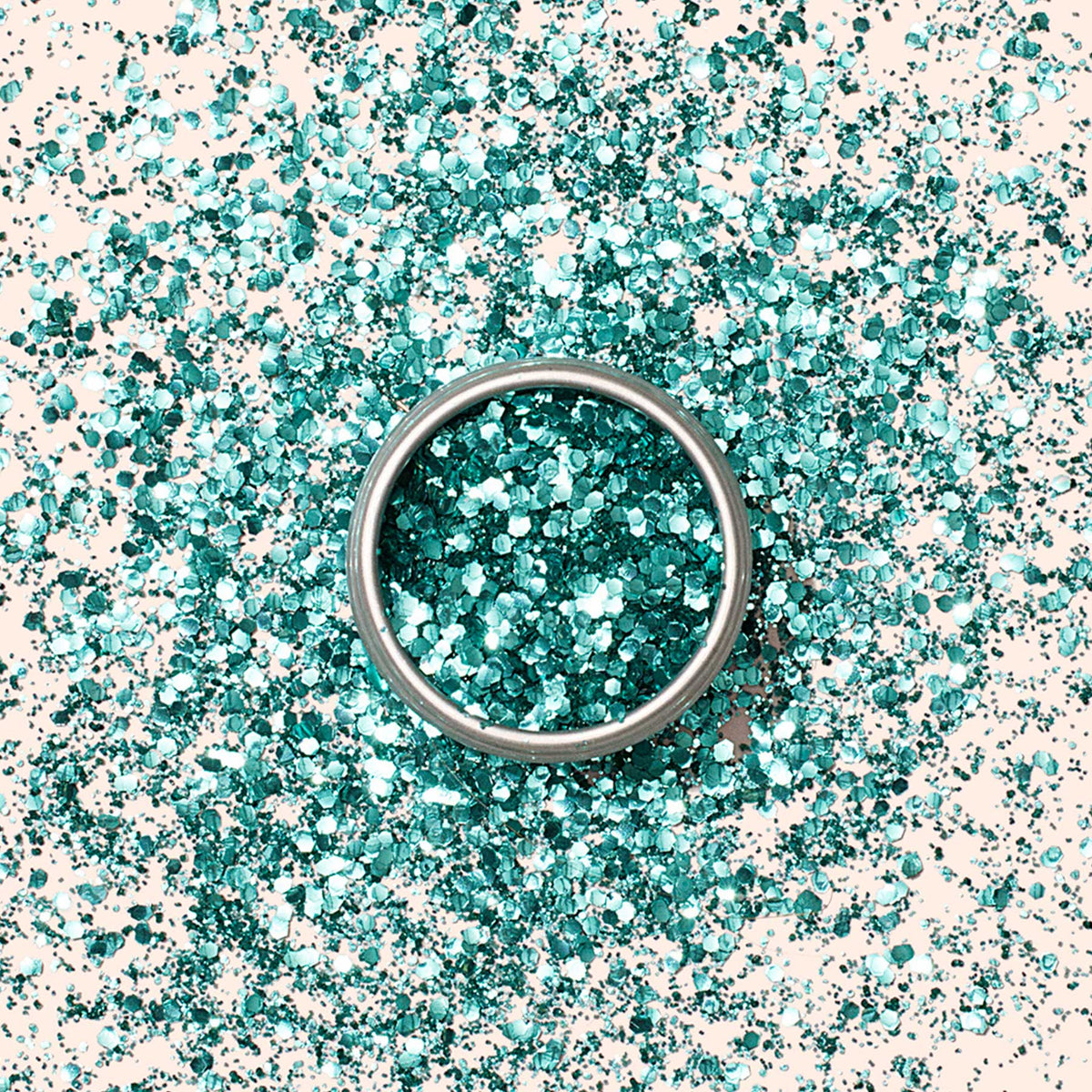 A silver ring rests on a surface sprinkled with Manucurist Biodegradable Glitter, with some shimmer scattered inside the ring, creating a sparkling and festive look.
