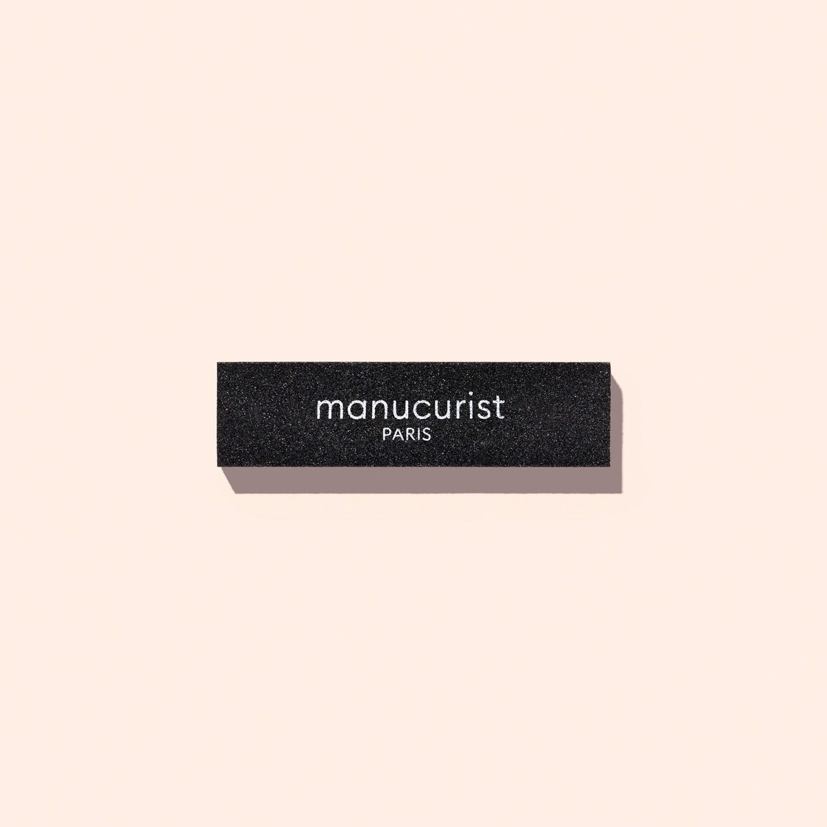 Rectangular black Manucurist Flash Removal Block nail buffer with the brand name printed in white.