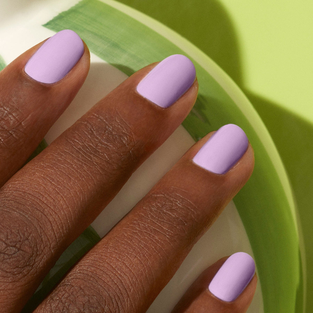 A close-up of a hand wearing Lisa Lilas by Manucurist, capturing subtle 90s vibes with its lilac nail polish.