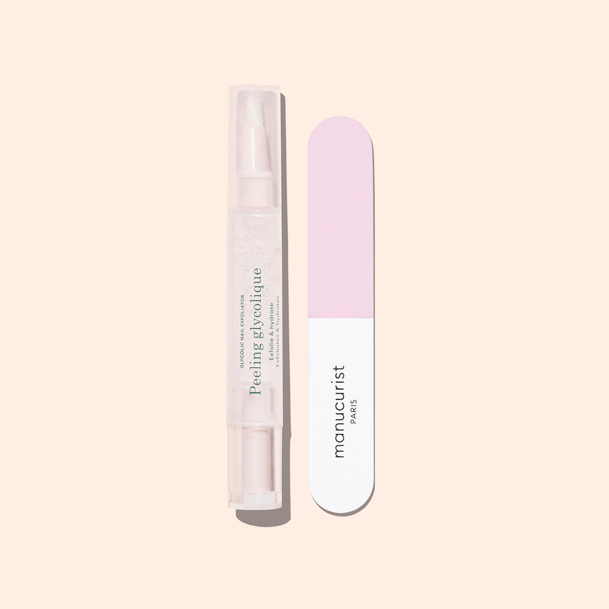 The Manucurist Glossy Booster Duo, featuring a gentle nail exfoliator and a pink-and-white nail file, rests on a pale beige background—ideal for achieving glossy nails.
