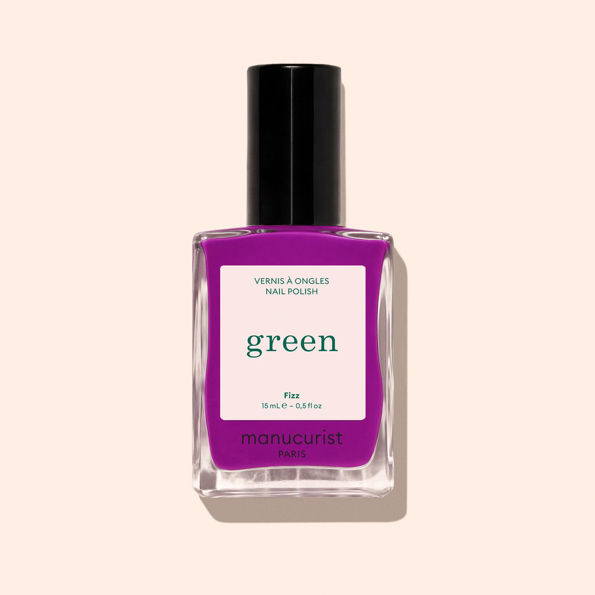 A bottle of Manucurist Fizz nail polish in a bright purple shade, featuring a black cap, is shown against a light beige background.