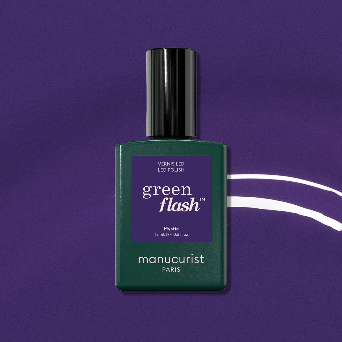 A bottle of Manucurist Mystic sits on a purple background with white curved lines. The dark green bottle has a black cap and purple label, ideal for an opaque gel polish finish.