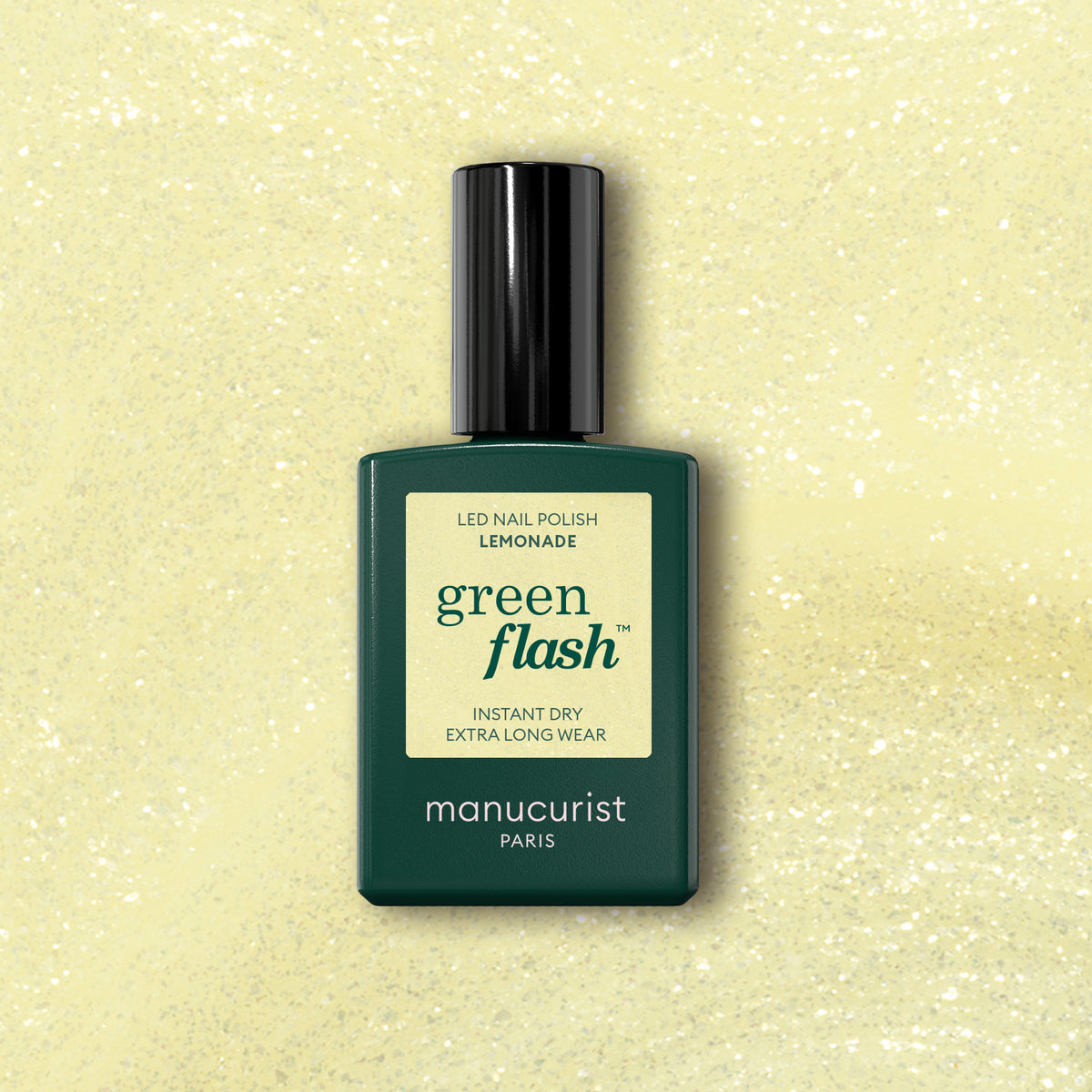 Manucurist Lemonade Green Flash LED gel polish, featuring a green rectangular base, black cap, and cream label, is displayed against a light yellow glittery background with shimmering highlights.