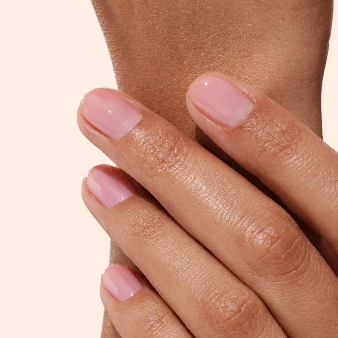 A close-up of a hand with neatly manicured nails painted in Manucurist’s Active Glow Blueberry, a plant-based polish, gently resting on a forearm against a light, neutral background.