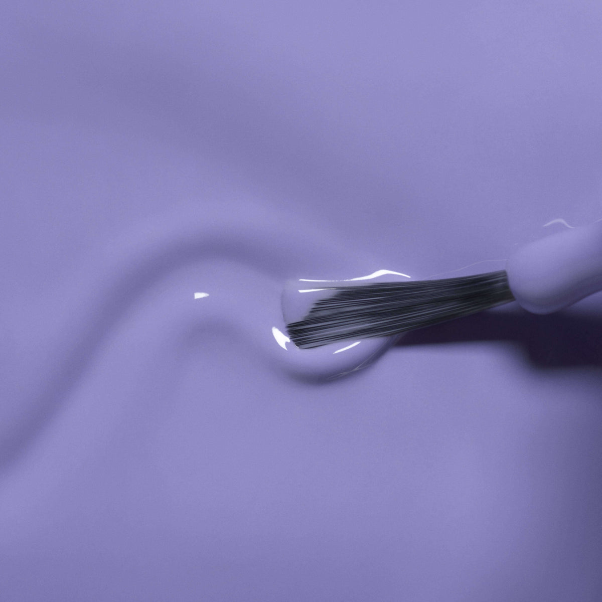 A close-up of a brush applying Manucurist’s Hector the Stégosaure, a glossy light purple kids nail polish with natural ingredients, to a smooth surface, creating a gentle swirl in the washable formula.
