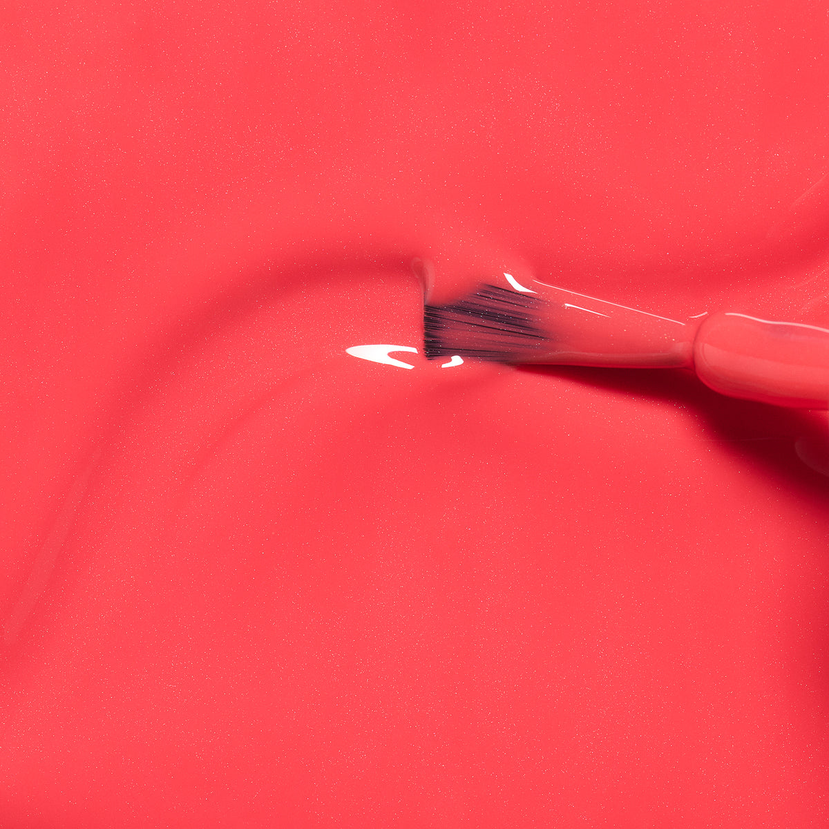 A close-up of a nail polish brush spreading glossy, bright pink Manucurist Kiki the Kitten kids nail polish with natural ingredients across a smooth surface.
