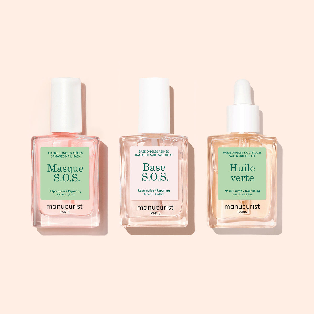 Three bottles of Manucurist nail care—S.O.S. Nail Mask, Green Base S.O.S., and Huile Verte—sit side by side on a beige background, perfect for supporting nail regeneration and repairing damaged nails.