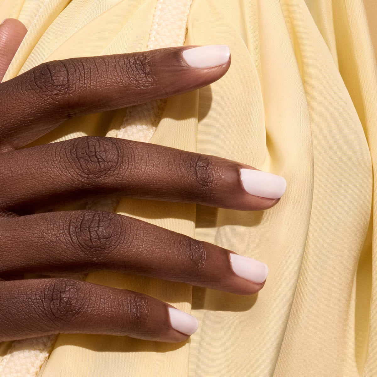A close-up of a dark-skinned hand with neatly manicured nails painted in Manucurist&