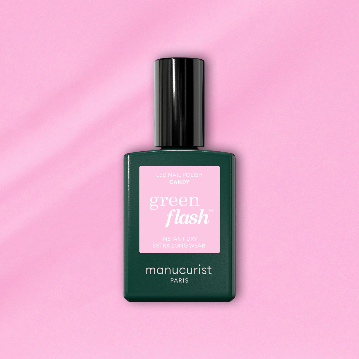 A green bottle of Manucurist-test Candy - Free LED polish with a black cap sits on a pink background. The pink label displays the product name and details.