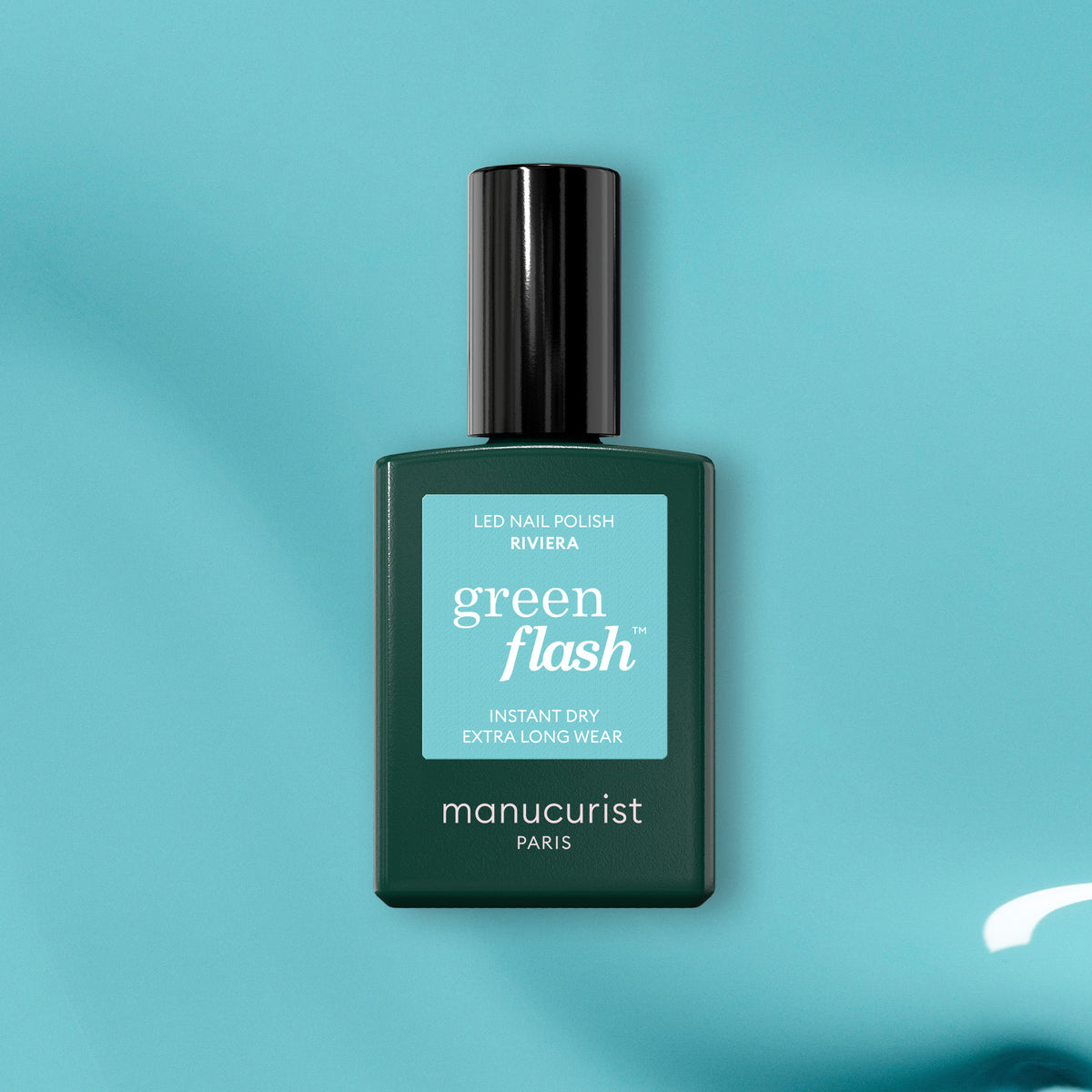 Manucurist’s Riviera Green Flash gel nail polish shines on a glossy turquoise surface—its label clearly visible. Add this vibrant turquoise blue shade to your collection for the perfect pop of color.