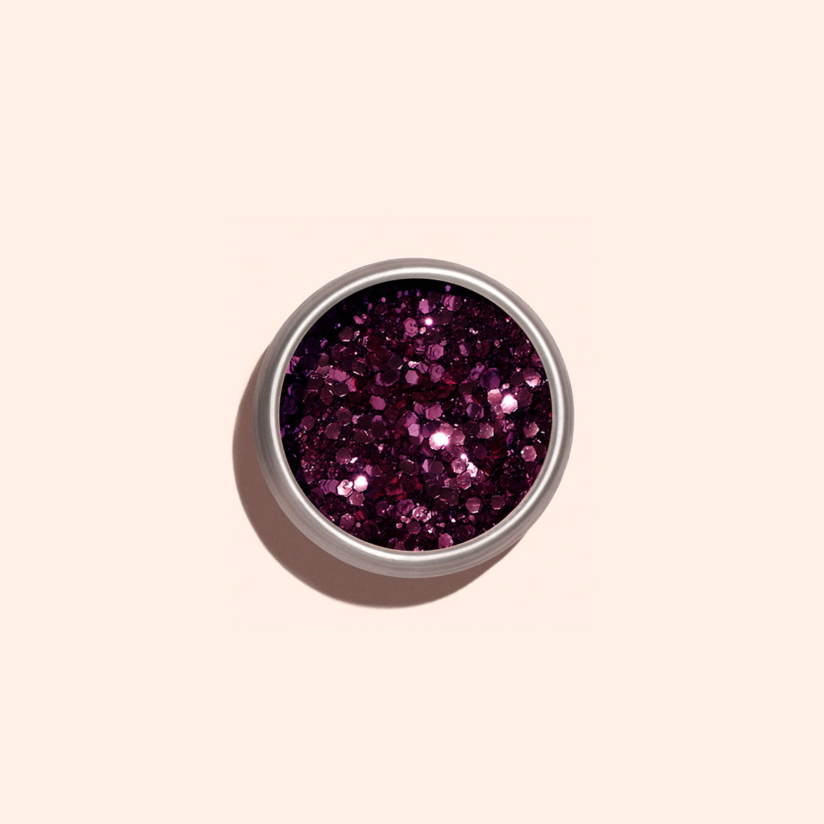 The Manucurist Bordeaux biodegradable glitter, a chunky and shiny dark pink eco-friendly glitter, is displayed in a small round container against a light beige background.
