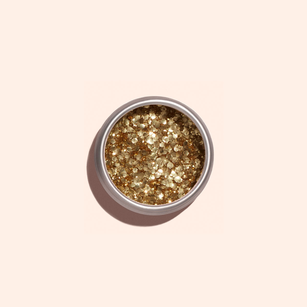 A round container of Manucurist Gold biodegradable glitter, ideal for nail art, is shown from above on a light beige background.