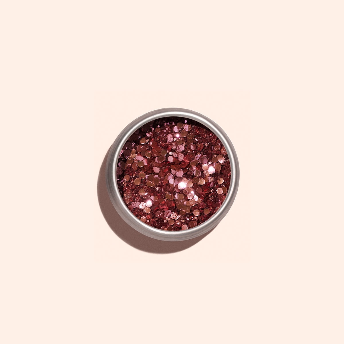 A small round container of Manucurist Pink Quartz biodegradable glitter sits on a light beige background. Ideal for nail art or mixing into gel polish, the chunky pink glitter sparkles beautifully in the light.