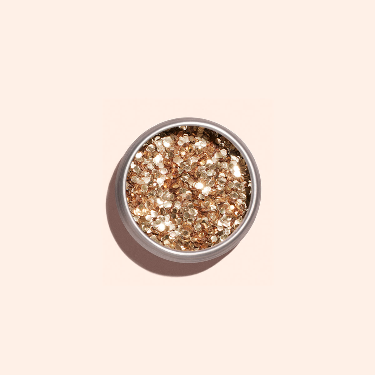 A round container of Manucurist Rose Gold biodegradable glitter, perfect for nail art, sits on a light beige background with a soft shadow to the left.