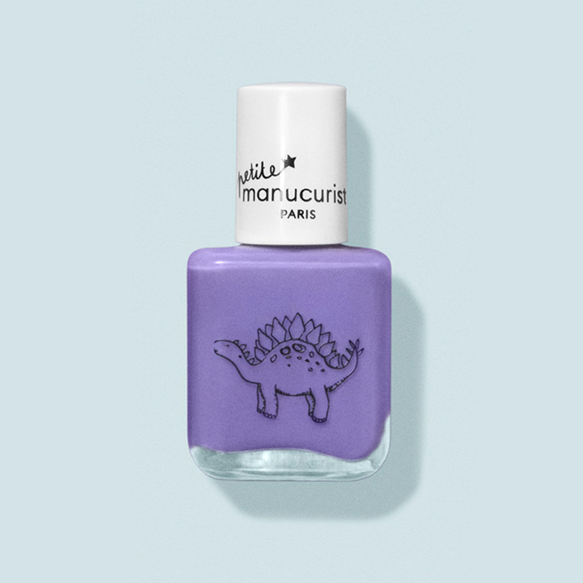 A bottle of purple kids nail polish called Hector the Stégosaure by Manucurist, with a white cap and simple black dinosaur on the label. The washable formula is set against a pale blue background.