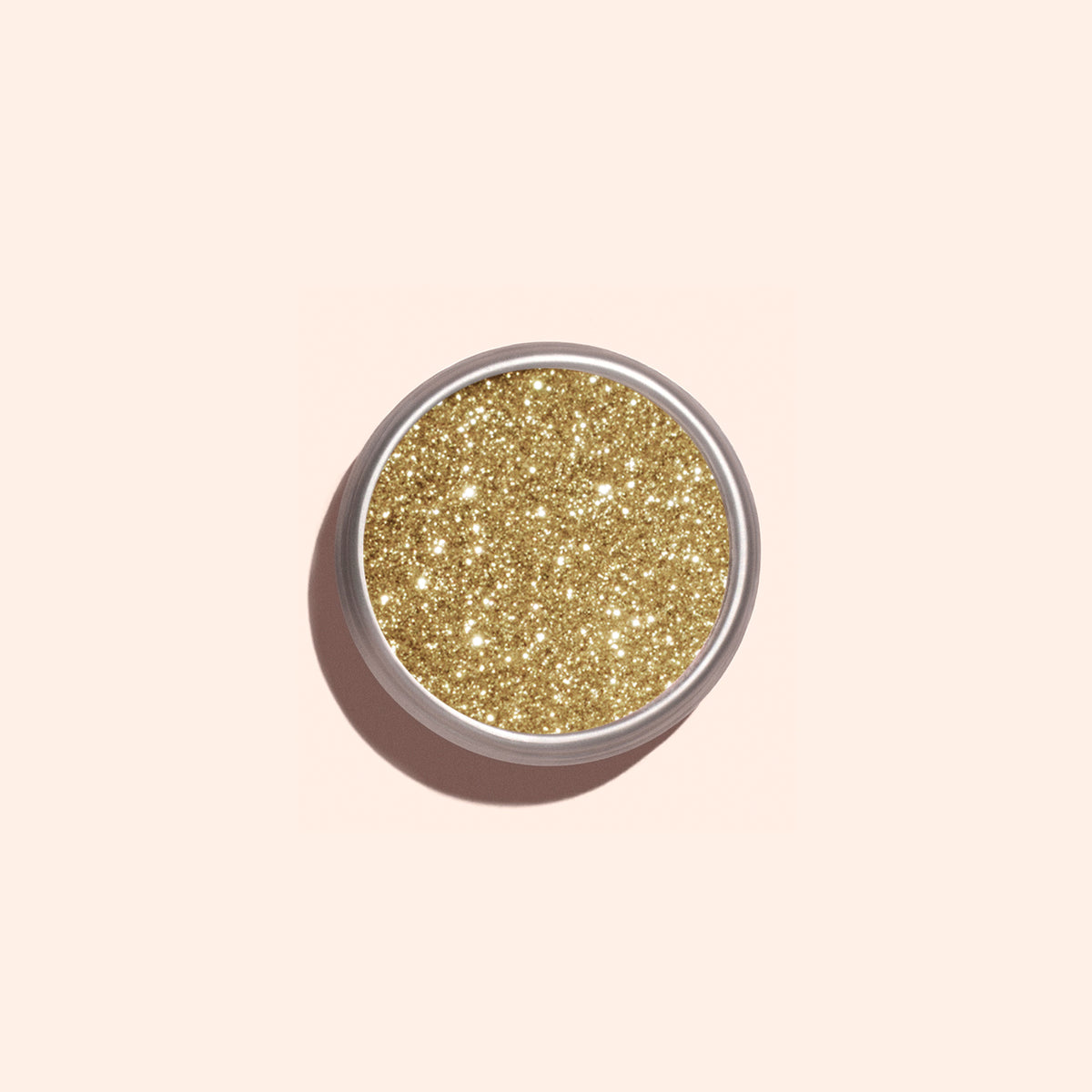 A round container of Manucurist Golden Chrome Powder, filled with shiny gold glitter and viewed from above on a light beige background, highlights its shimmering allure.
