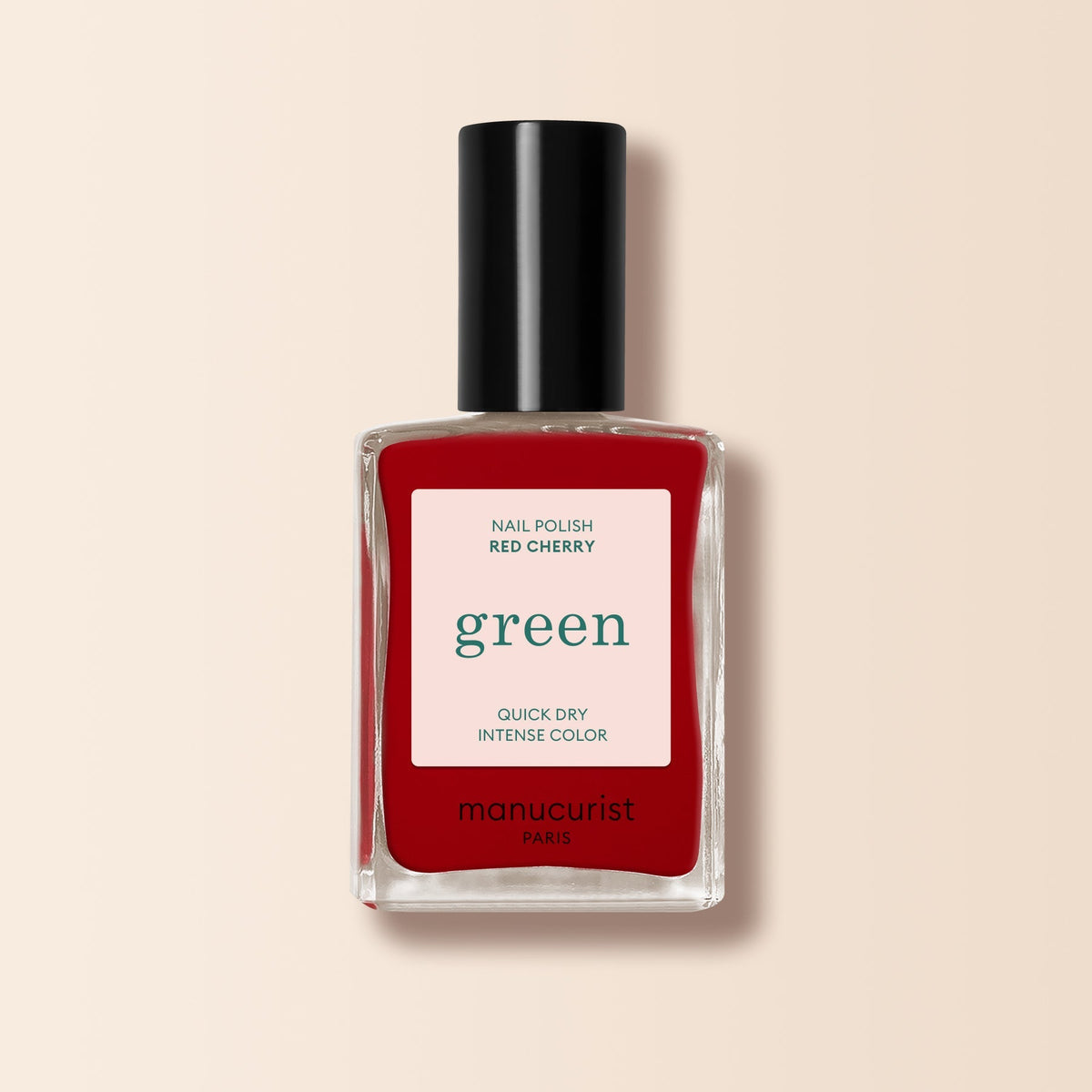 A bottle of Manucurist Red Cherry nail polish features a black cap, clear glass, and a beige label reading "green - quick dry intense color.
