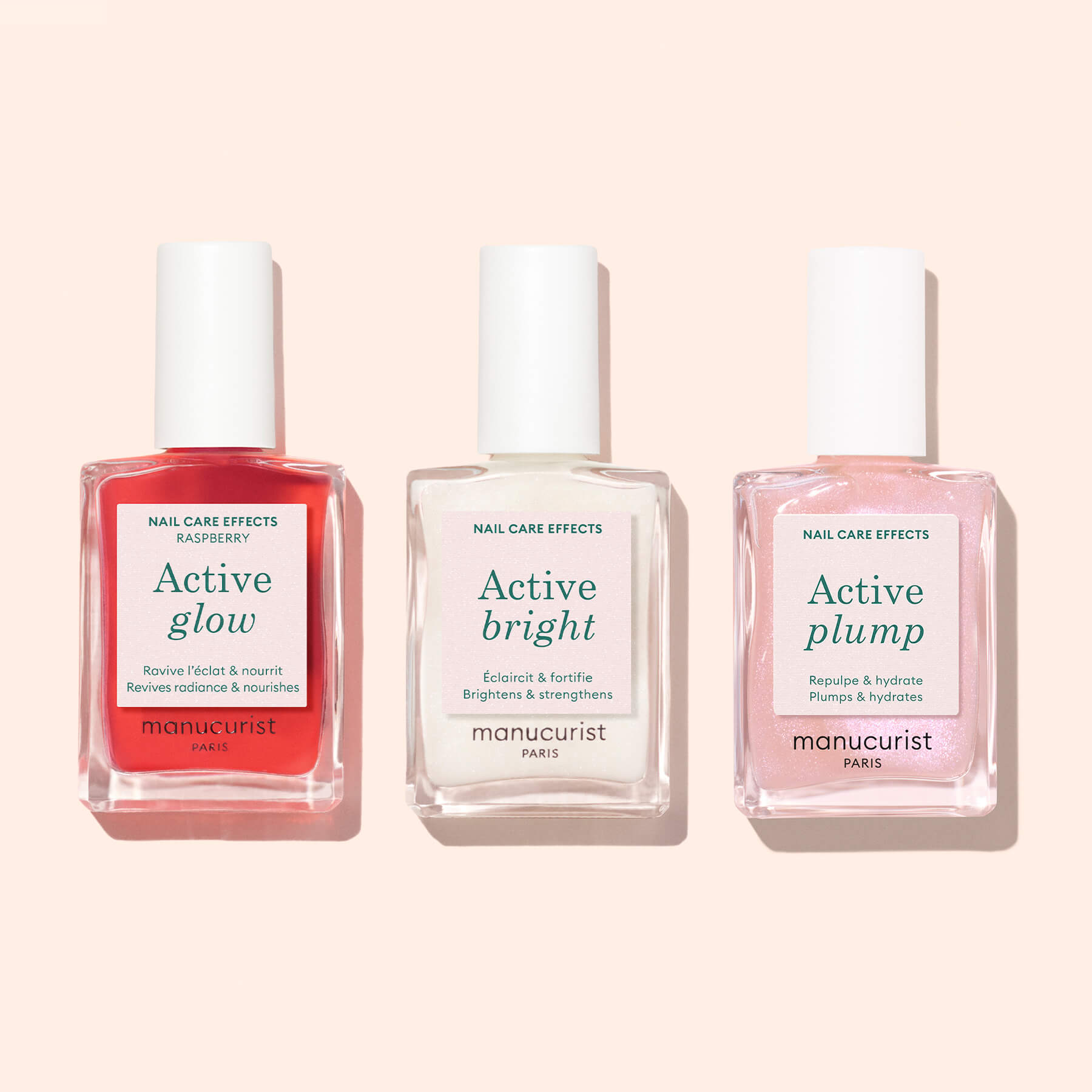 Three bottles of Manucurist nail care products with plant-based formulas—Active Glow Raspberry (red), Active Bright (white), and Active Plump (pink)—are lined up on a light pink background.