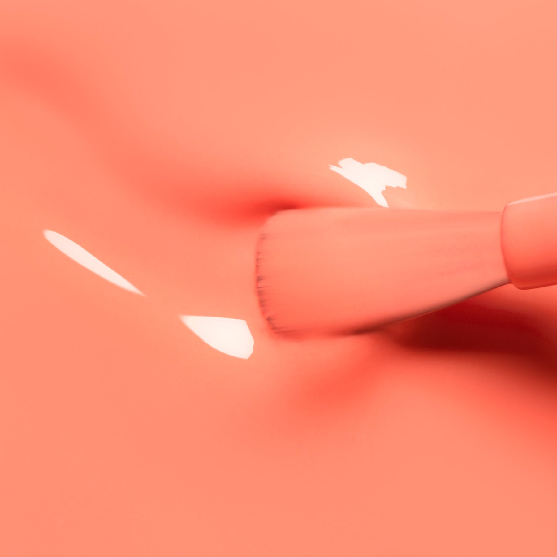 A makeup brush gently presses against Manucurist’s Tangerine nail polish, creating soft indentations and shiny reflections inspired by vibrant ‘90s style.